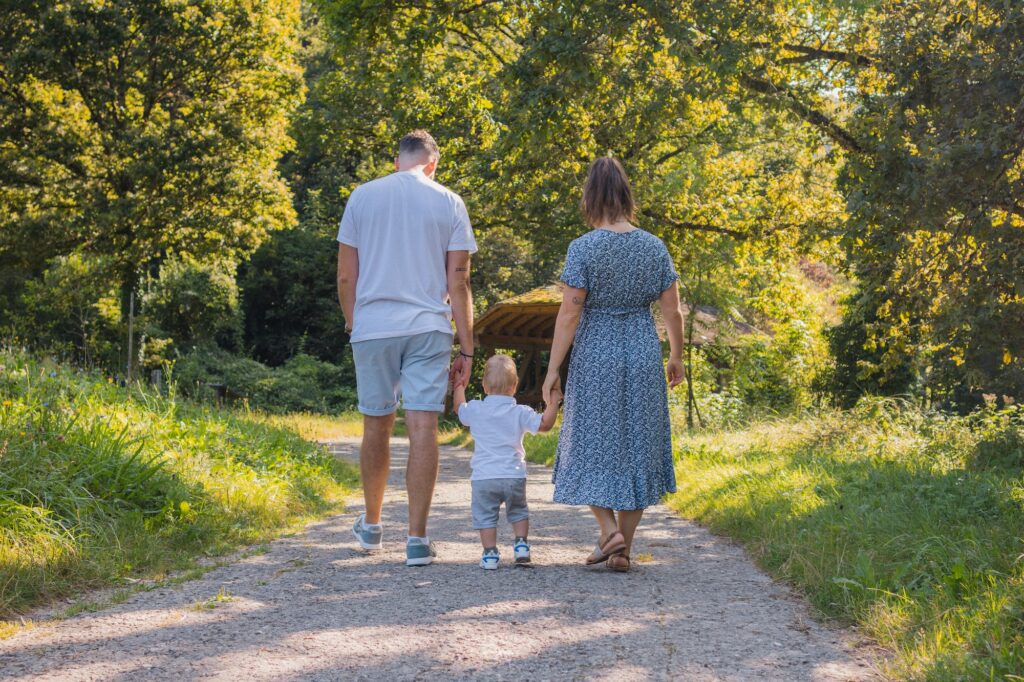 Séance photo famille en forêt, parents et enfant de dos sur un chemin, photographe famille Suisse romande