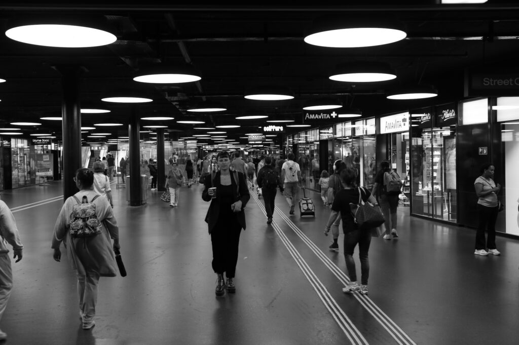 Photographie de rue noir et blanc, hall de gare animé, reportage urbain Suisse